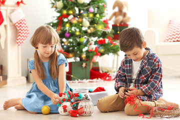 Cute children making Christmas handicrafts on floor