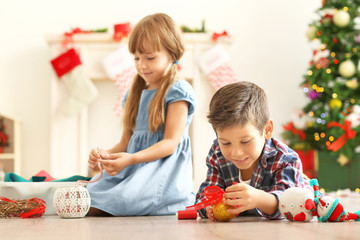 Cute children making Christmas handicrafts on floor