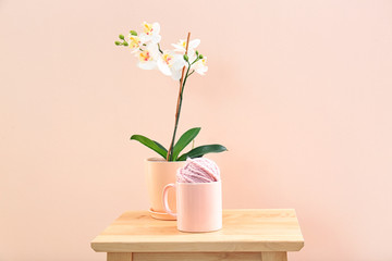Orchid and apricot cup with thread ball on table against trendy color background