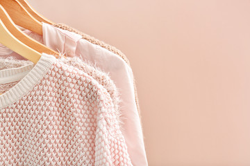 Apricot clothes on hangers against trendy color background