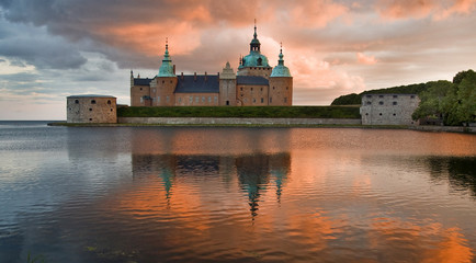 Kalmar Slott med röd himmel solnedgång speglar i vattnet - obrazy, fototapety, plakaty