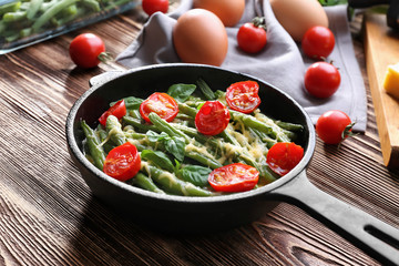 Frying pan with delicious green bean casserole on wooden table