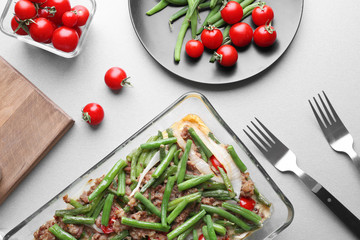 Baking dish with yummy green bean casserole on kitchen table