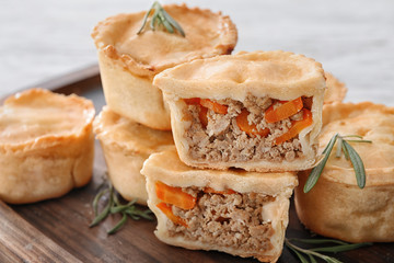 Delicious little meat pies on wooden tray