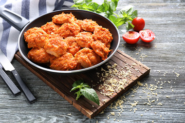 Frying pan with tasty sausage balls on wooden table