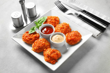 Plate with tasty sausage balls and sauces on table