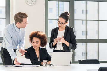 Young female employee asking for advice her helpful experienced colleagues in the office