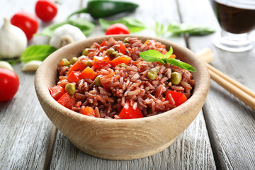 Bowl with brown rice and vegetables on wooden table