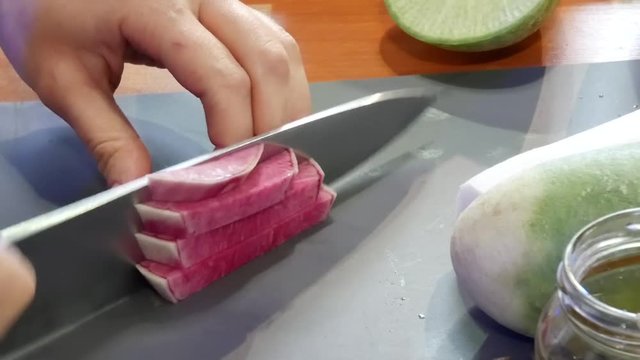 Cutting Pink Chinese Red Meat Radish Called Watermelon Radish at Market On Kitchen's Board at Restaurant or Home. Preparation for Cooking Fresh Vegetables