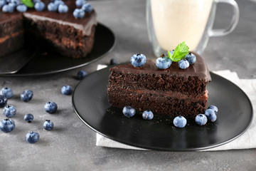 Black plate with delicious chocolate cake on grey background