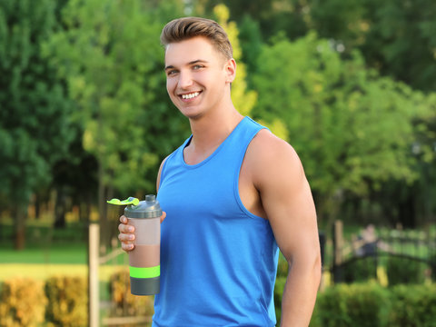 Sporty young man with protein shake outdoors