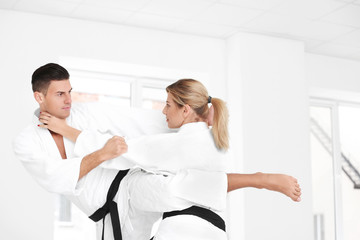 Fototapeta premium Young man and woman practicing karate in dojo