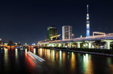 Skyline of Tokyo with skytree and river and lighttrails of boat at night, Tokyo, Japan