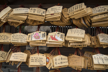 Wooden prayer tablets with Japanese characters and pictures in a shrine in Japan