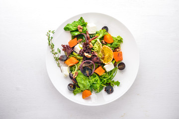 Pumpkin and fresh vegetables salad. Italian cuisine. Top view. Free space for text. On a wooden background.