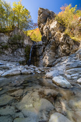 Dalla roccia un rivolo d'acqua scorre in mezzo ai colori autunnali 
