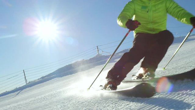 SLOW MOTION CLOSE UP: Young adult recreational skier enjoys idyllic perfect weather in cold winter. Skiing alone on perfectly groomed ski piste at ski resort. Located at the top of the mountain