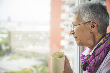 Senior elderly woman enjoying her morning cup of coffee and looking forward to a beautiful day