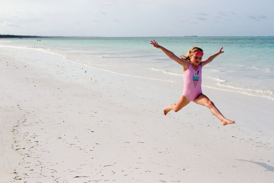 A little girl jumping athletically on a tropical beach