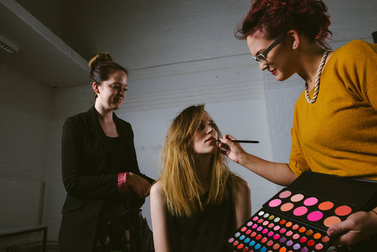 Makeup Artists prepairing female fashion model for photo shooting