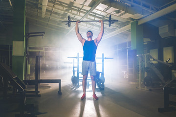 The sportsman lifting a barbell in the gym