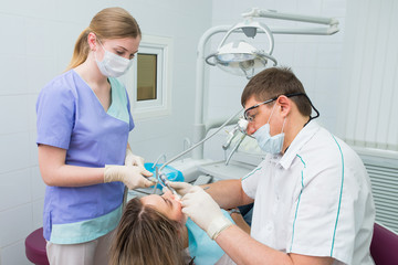 dentists and assistant treating teeth of woman patient
