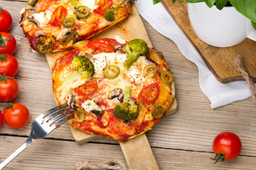 Tasty Italian homemade mini pizzas with broccoli, feta and olives served on wooden cutting board.