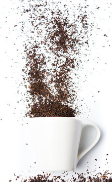 Black tea grains falling from a teacup