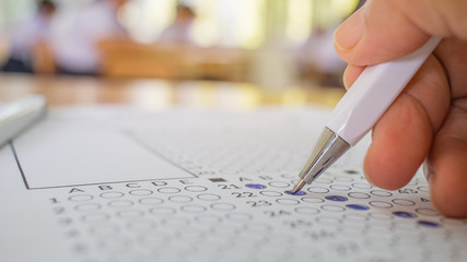 Students hand testing doing examination with pen drawing selected choice on answer sheets in school...