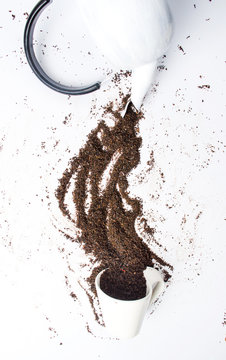 Black Tea Grains Falling Into Teacup From Kettle