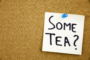 A yellow sticky note writing, caption, inscription Phrase SOME TEA in black ext on a sticky note pinned to a cork notice board