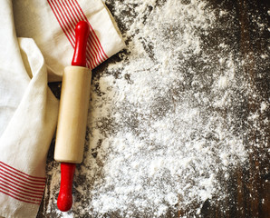 Classic wooden rolling pin and dusting of flour on wooden background