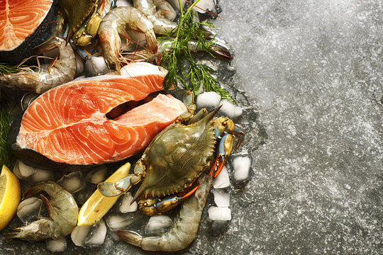 Fresh seafood: salmon steak, shrimps and crabs on stone with copy space