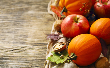 Autumn pumpkins and apples with fall leaves on wooden background with copy space. Autumn composition