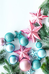 Christmas decoration pattern. Pink and blue stars and balls near pine branches on white background top view copyspace