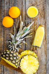Freshly squeezed pineapple juice near fruit slices on wooden background top view