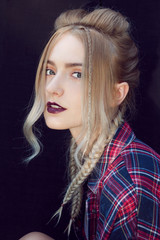 Close up of beautiful young woman with strong dark makeup and purple lips. Professional modern stylish fashionable hairstyle. Created from small and large braids and loose hair.