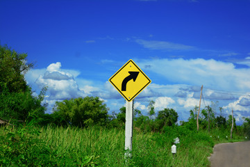 the yellow sign beside the road means to beware the curve ahead