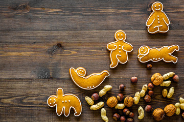 Healthy food for sportsman. Cookies in shape of yoga asanas near nuts on dark wooden background top view copyspace