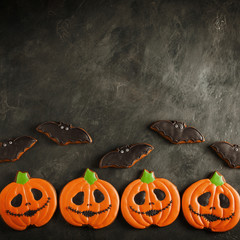 Halloween pumpkin and bats cookies overhead shot with copy space. On dark concrete background