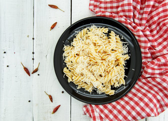 Fusilli pasta with grated parmesan cheese on rustic wooden table. Italian cuisine. Healthy homemade food