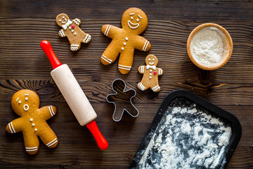 Make gingerbread cookie for new year 2018. Gingerbread man, rolling pin, flour on dark wooden background top view