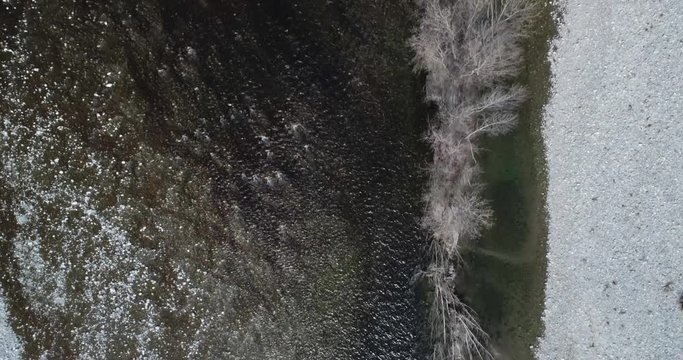 moving overhead backward over river bed in autumn or winter. Outdoor sunny nature scape riverbed near forest wild aerial establisher.4k top view drone flight establishing shot