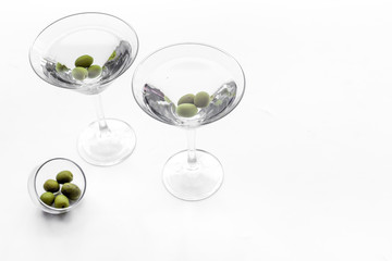 Martini cocktail in glass with olives at the bottom on white background top view copyspace
