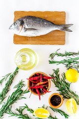 Preparing dorado with spices rosemary, pepper, chili, lemon. White background top view
