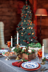 Beautiful Christmas family dinner table at the nicely decorated New Year interior with Christmas tree