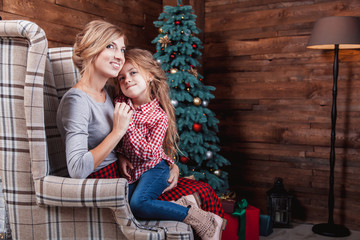 Beautiful happy mother with her daughter embrace in New Year interior with Christmas tree