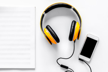 Worktable of composer today. Headphones, phone, music notes on white background top view