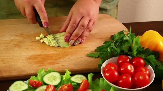 A woman cuts the avacado peeled from its peel, to make a salad. Shot with a cart from left to right