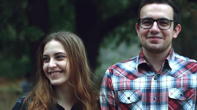 Happy young couple hipster, look at the camera and at each other during a summer walk in the park. 4k